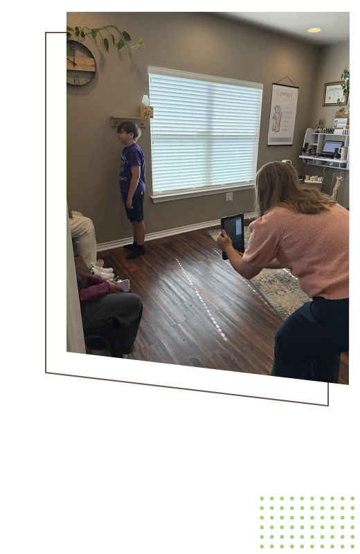 Dr. Amanda Ulloa holding a tablet while another person stands against a wall in a room with seated individuals.